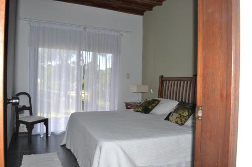 1 dormitorio con cama, ventana y silla en Arenas del Mar, en José Ignacio