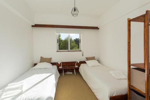 twee bedden in een kamer met een raam bij Carcavelos Beach Apartment in Cascais