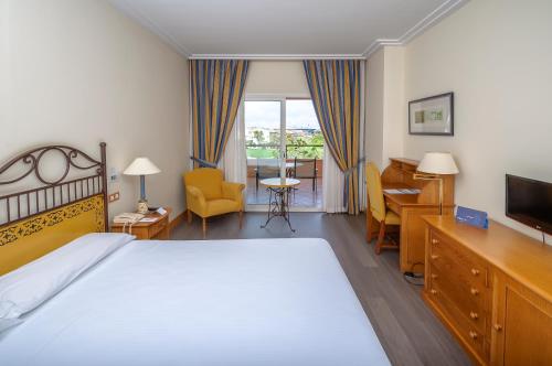 a hotel room with a bed and a desk and a television at Hotel Alicante Golf in Alicante