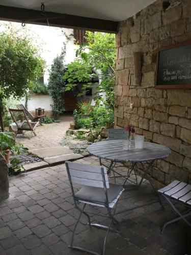 un patio con mesa, sillas y pared de piedra. en Vivo-Vino en Weisenheim am Sand