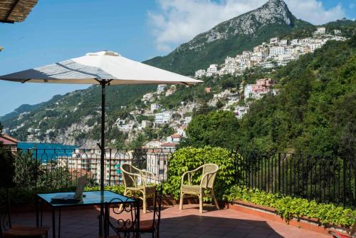 a table and chairs and an umbrella on a balcony with a mountain at La Valle Delle Najadi in Vietri sul Mare