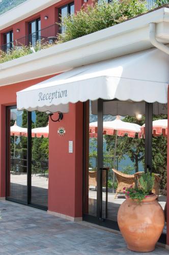 a restaurant with an awning in front of a building at Hotel Oasi Beach in Malcesine