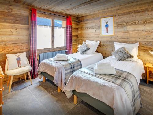 a bedroom with two beds in a log cabin at Chalet Alyssum - OVO Network in Le Grand-Bornand