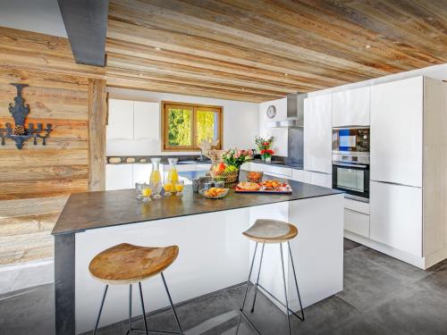 a kitchen with white cabinets and a counter with stools at Chalet Alyssum - OVO Network in Le Grand-Bornand