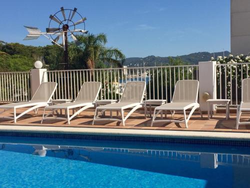 a group of chairs sitting next to a swimming pool at Es Mitjorn Hotel in San Antonio