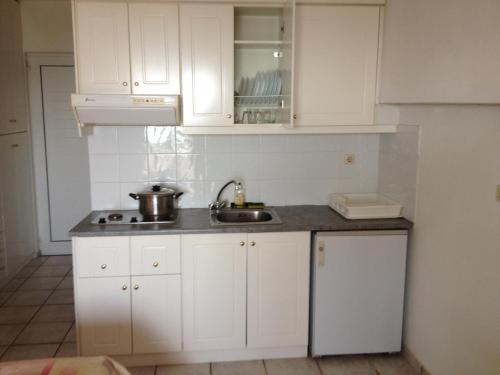 uma cozinha com armários brancos e um lavatório em Gikas Apartments em Marmari