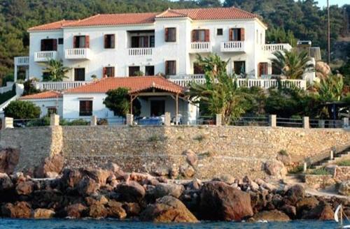 a large white house sitting on top of a rock wall at Alkioni Studios in Karlovasi