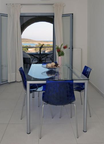 a glass dining table with blue chairs in a room at Astarte Sea Villas in Dhiakofti