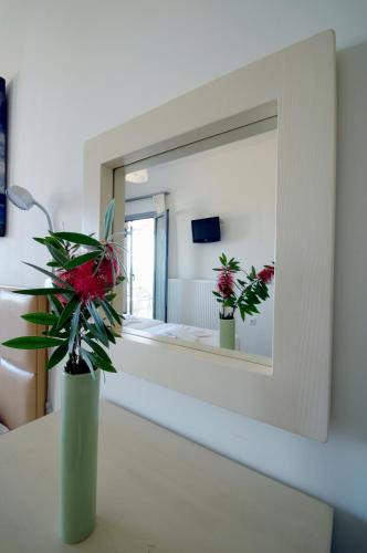 a vase with flowers on a table in front of a mirror at Astarte Sea Villas in Dhiakofti