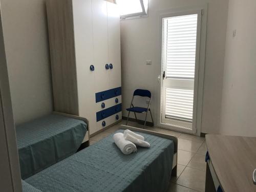 トッレ・ラピッロにあるCasa Gadaのベッド2台と青い椅子が備わる客室です。