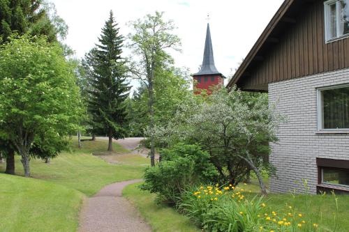 a path next to a house with a church at Trunna Vandrarhem & Konferens in Orsa