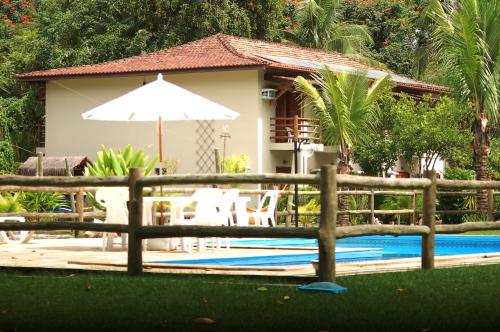 a fence in front of a house with a pool at Pousada Praia de Itamambuca in Ubatuba