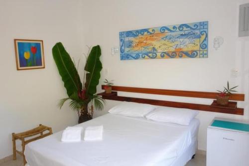 Un dormitorio con una cama blanca y una planta en Pousada Praia de Itamambuca en Ubatuba