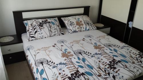 łóżko z kwiatową narzutą i poduszkami w obiekcie Apartman Zoja w miejscowości Mali Lošinj