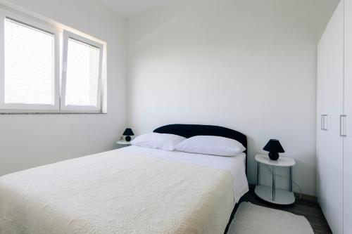 Habitación blanca con cama y ventana en Apartments Luce, en Zadar