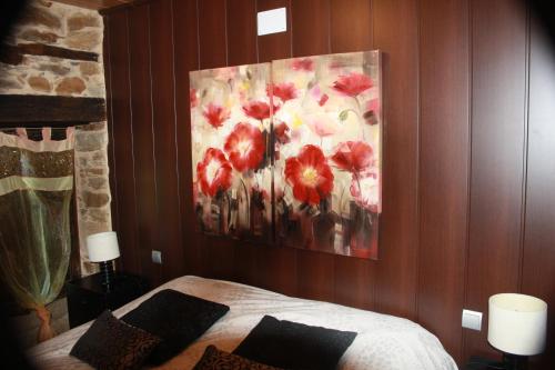 a bedroom with a painting of red flowers on the wall at Alojamiento Luz de Hadas in Sampil