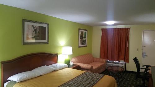 a hotel room with a bed and a chair at American Inn Columbia in Columbia