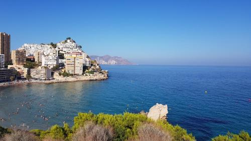 a group of people swimming in the water near a city at Penthouse Beach Apartment in Cala de Finestrat