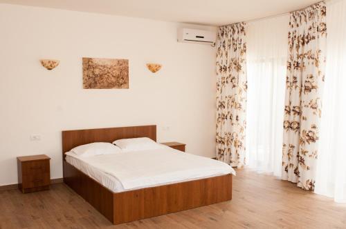a bedroom with a bed with white sheets and curtains at Complex Adal in Eforie Nord