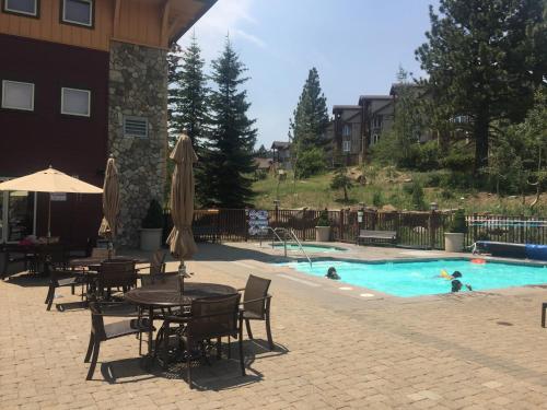 a pool with tables and chairs and people swimming in it at Sunstone Lodge by 101 Great Escapes in Mammoth Lakes