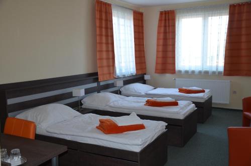 three beds in a room with orange curtains at Penzión Rocket Club in Lučenec
