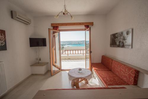 Una sala de estar con un sofá rojo y una mesa. en Bay View Apartments, en Sitia