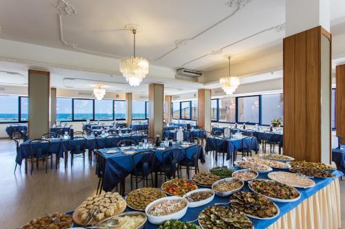 una línea de buffet con mesas azules y sillas con comida en Hotel Miramare, en Gatteo a Mare