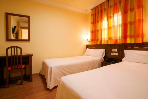 a hotel room with two beds and a mirror at Hostal Victoria I in Madrid