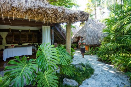 a woman walking past a house with a thatch roof at Castaway Island, Fiji in Castaway Island
