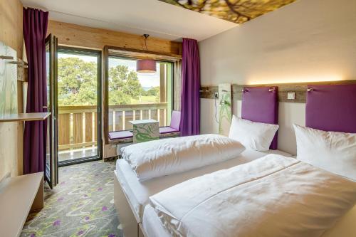 two beds in a room with purple walls and windows at Explorer Hotel Berchtesgaden in Schönau am Königssee