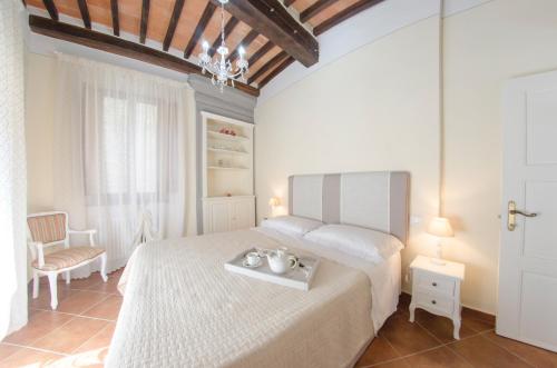 Un dormitorio con una cama blanca y una silla. en La Nicchia - Serena Tuscany Homes, en Cortona