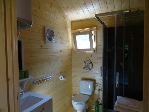 uma casa de banho em madeira com um WC e um chuveiro em Lesny domek em Międzyzdroje