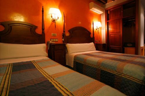 two beds in a room with orange walls at Hostal Victoria I in Madrid