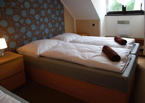 two beds in a hotel room with white sheets at Hotel Veveří in Veverská Bítýška
