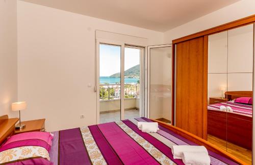 ein Schlafzimmer mit einem großen Bett und einem Balkon in der Unterkunft Apartments Lille in Herceg-Novi