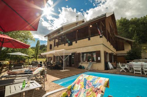 une maison avec une piscine à côté d'un bâtiment dans l'établissement Chalet les Moineaux Chambres d'Hôtes, à Jausiers