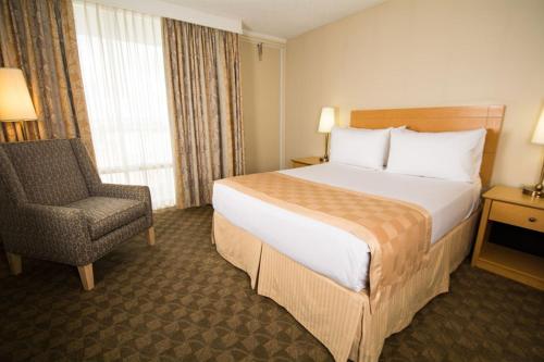 a hotel room with a bed and a chair at Edmonton Inn and Conference Centre in Edmonton
