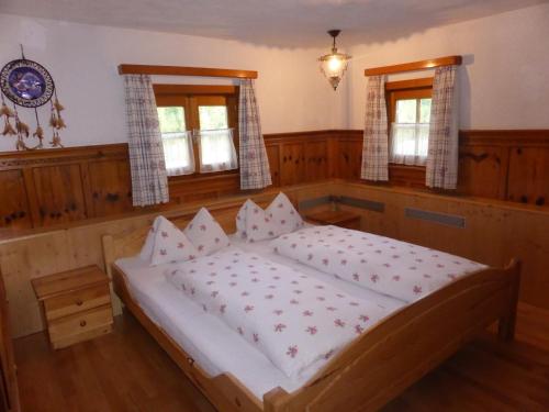 a large bed in a room with two windows at Schwaighof in Oberau