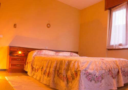 a bedroom with a bed and a dresser and a window at Balcon des Alpes in Teglio
