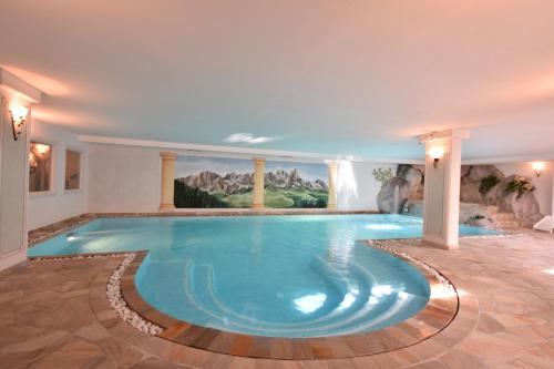 a swimming pool in a hotel with a painting on the wall at Residence Pez Gajard in San Martino di Castrozza