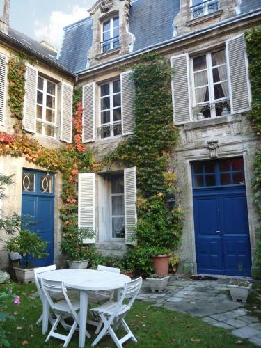 a white table in front of a building with blue doors at Jardin et Hotel Particulier in Bayeux