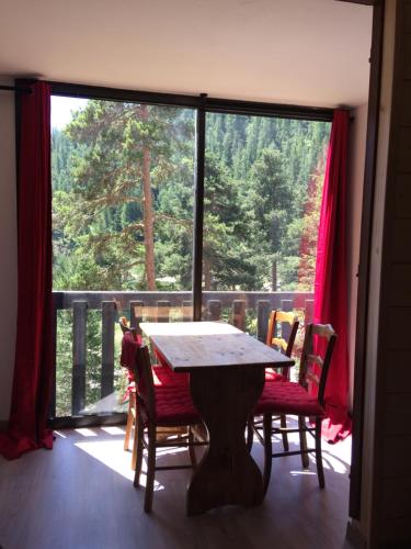 a table and chairs in a room with a large window at le mélèze in Valdeblore