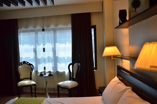 a bedroom with a bed and two chairs and a window at Oriental Zen Suites in Manila