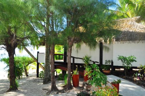a resort with trees and a bench in the sand at Tamanu Beach in Arutanga