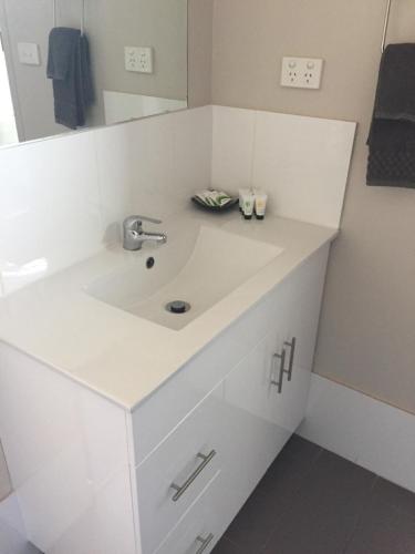 a white bathroom with a sink and a mirror at The Argent Motel in Broken Hill