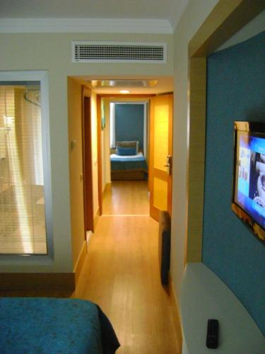 a room with a bedroom with a television and a hallway at Limak Limra Hotel & Resort Kemer - Kids Concept in Kemer