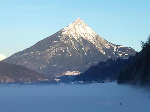 a snow covered mountain in front of a lake at Apartments Gabl in Schönwies