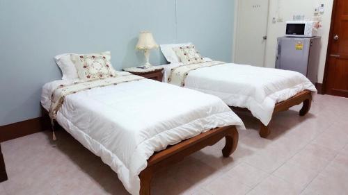two beds with white covers in a room at Chanathinat Place in Udon Thani