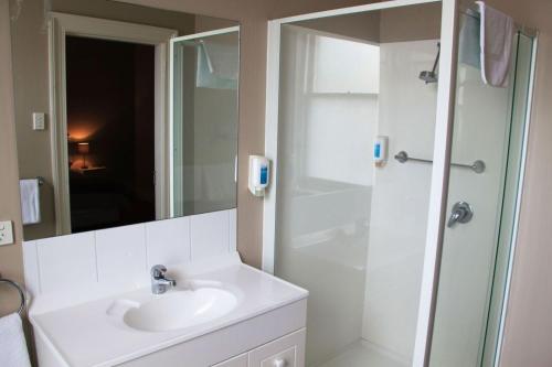 een witte badkamer met een wastafel en een douche bij Sporties Hotel in Launceston