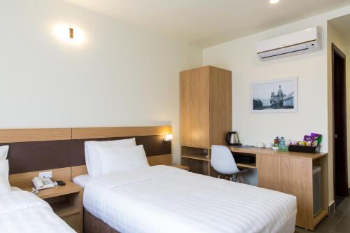 a hotel room with two beds and a desk at Punt Hotel in Hai Phong